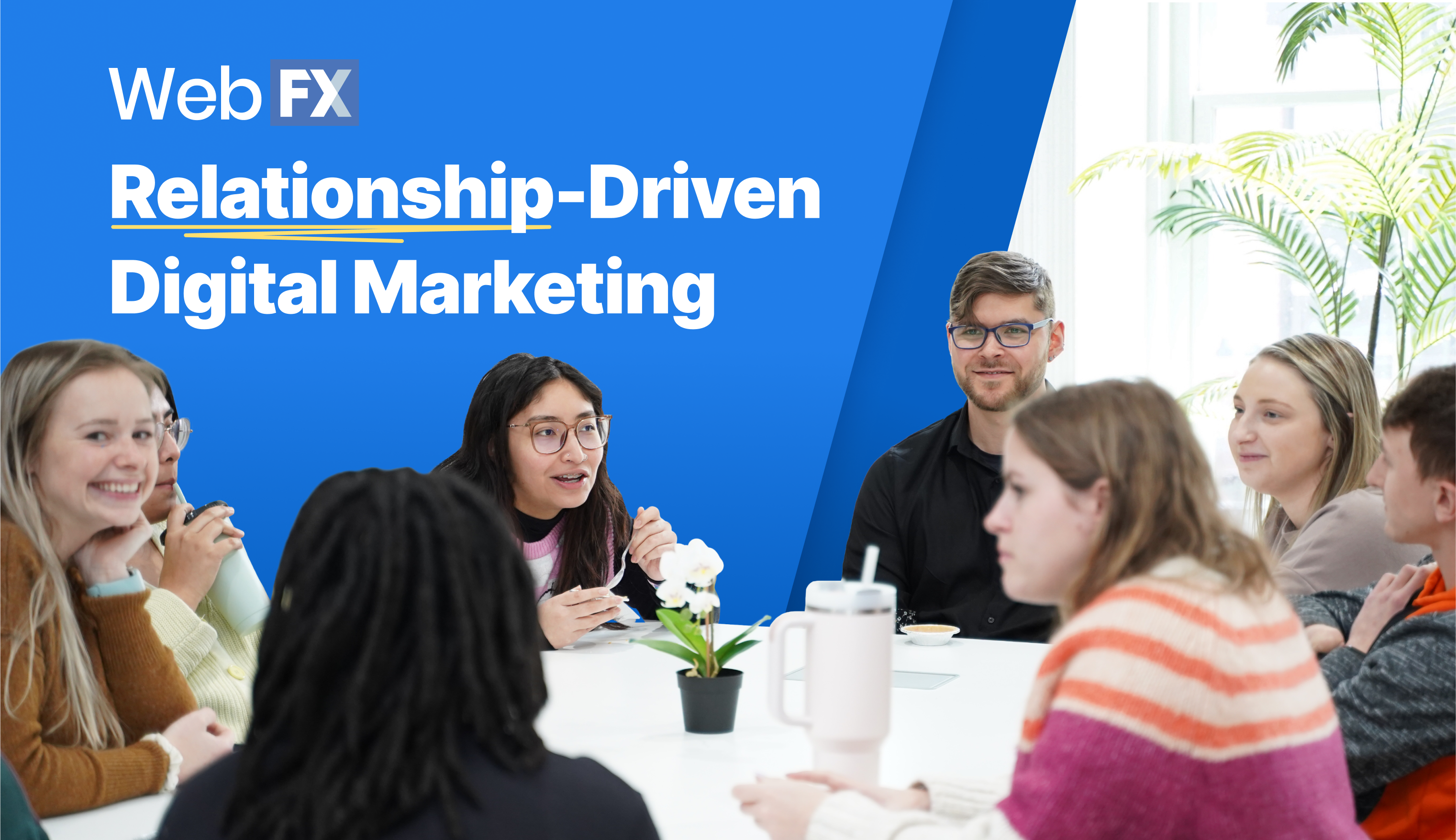 A group of people in a casual meeting around a table with a potted plant, in a room with a large window, under a blue banner with the text 'Web FX Relationship-Driven Digital Marketing'.